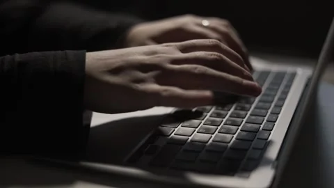 Close-up of hands typing on a laptop keyboard in dramatic low light Stock Footage 339173636