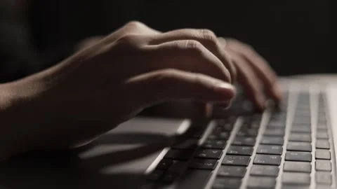 Close-up of hands typing on a laptop keyboard in low light conditions Stock Footage 339173969