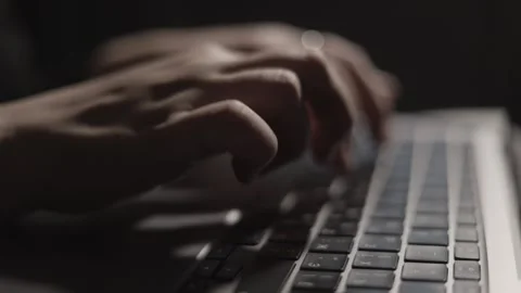 Close-up of hands typing on a laptop keyboard in low light conditions Stock Footage 339174054