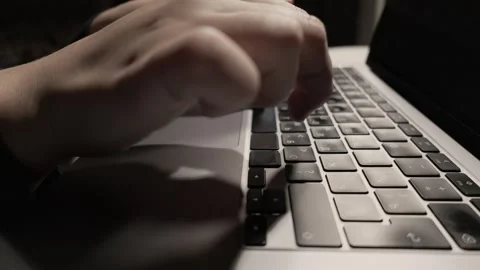 Close-up of hands typing on a laptop keyboard in low light conditions Stock Footage 339174085