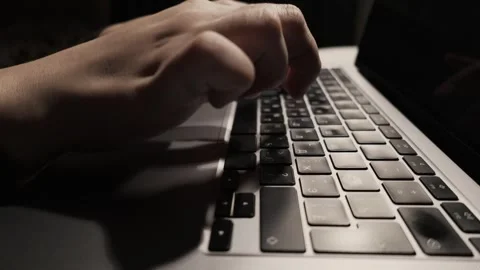 Close-up of hands typing on a laptop keyboard in low light conditions Stock Footage 339174177