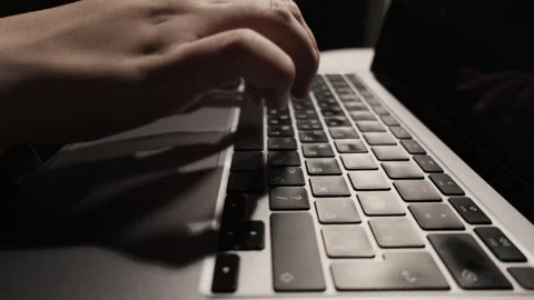 Close-up of hands typing on a laptop keyboard in low light conditions Stock Footage 339174186