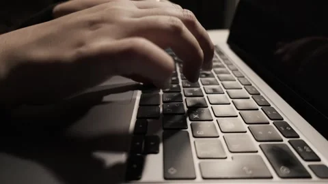 Close-up of hands typing on a laptop keyboard in low light conditions Stock Footage 339174271