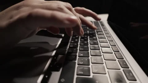 Close-up of hands typing on a laptop keyboard, capturing the motion and focus of Stock Footage 339174294
