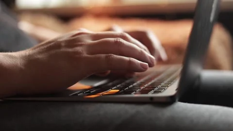 Close-up of hands typing on a laptop keyboard with warm backlighting Stock Footage 340264312