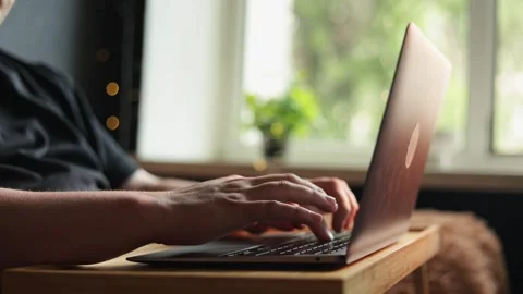 Close-up of hands typing on a laptop keyboard in a cozy indoor setting Stock Footage 340264443