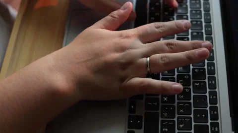Close-up of hands typing on a laptop keyboard with a ring on one finger Stock Footage 340265445