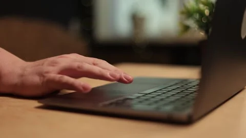 Close-up of hands typing on a laptop keyboard in a dimly lit room Stockbeeldmateriaal 341737751