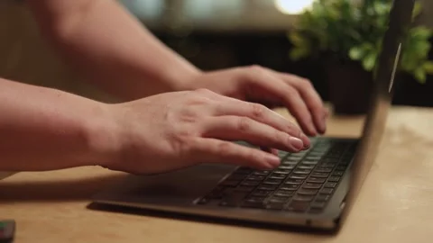 Close-up of hands typing on a laptop keyboard in a warm, inviting setting Video stock 341737815
