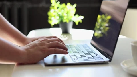 Close-up of hands typing on a laptop keyboard next to a coffee cup Vidéo 342280432