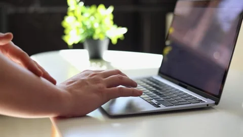 Close-up of hands typing on a laptop keyboard in a bright, modern workspace Stockbeeldmateriaal 342280434