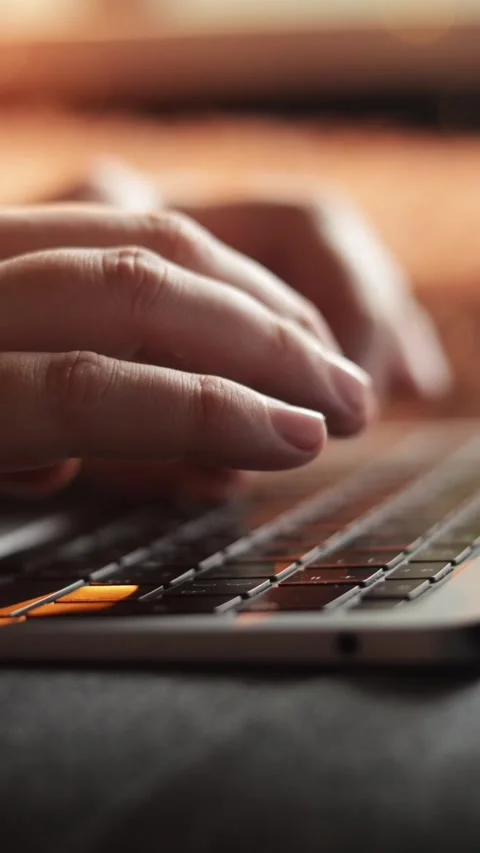 Close-up of hands typing on a laptop keyboard with warm backlighting Stock-Footage 343838115