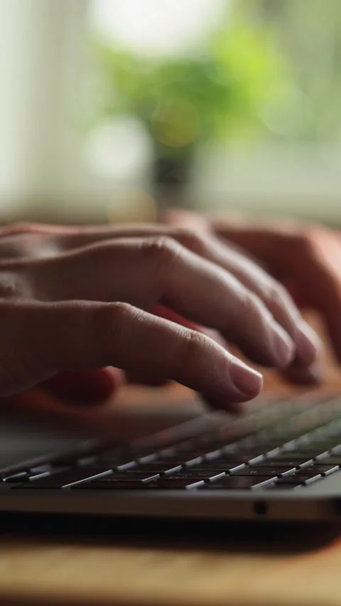 Close-up of hands typing on a laptop keyboard with soft natural light filtering Vidéo 343838117