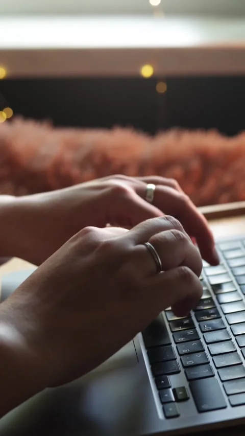 Close-up of hands typing on a laptop keyboard with soft bokeh lights in the Stockbeeldmateriaal 343838171