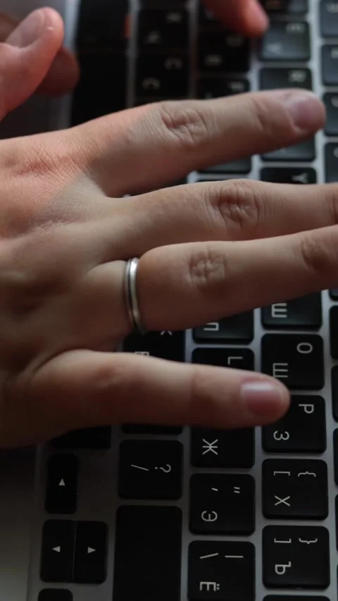 Close-up of hands typing on a laptop keyboard with Cyrillic letters Stockbeeldmateriaal 343838180