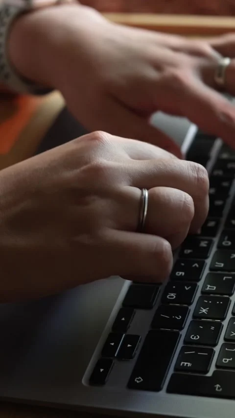 Close-up of hands typing on a laptop keyboard with a wedding ring visible Stock Footage 343838186