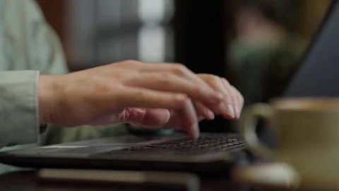A Close-Up of Hands Typing on a Laptop Keyboard While Enjoying a Cup of Coffee Stock Footage 344799903