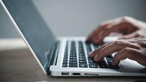 Close-up of hands typing on a laptop keyboard. The laptop is open and the k.. 库存照片