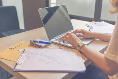 Close up of hands typing laptop next to graph document Stock Photos