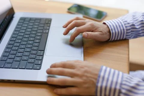 Close-up hands typing on a laptop, working on the touchpad. Stock Photos