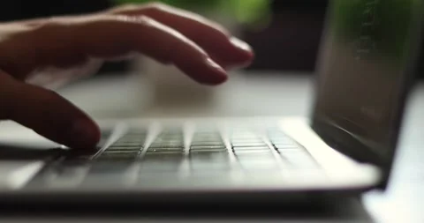 Close-up of hands typing quickly on a laptop keyboard in soft natural light Stock Footage 339075175
