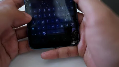 Close-up of hands typing on a smartphone with a cracked screen Stock Footage 317736821