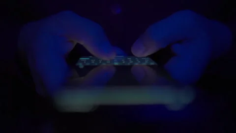 A close-up of hands typing on a smartphone in the dark Stock Footage 334517603