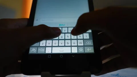 Close-up of hands typing on a smartphone keyboard in low light Stock Footage 316800050