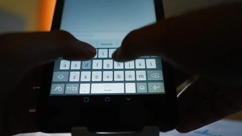 Close-up of hands typing on a smartphone keyboard in low light Stock Footage 317737064