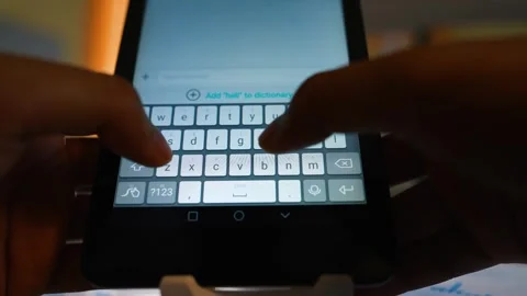 Close-up of hands typing on a smartphone keyboard in low light Stock Footage 317737068