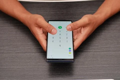 Close Up Of Hands Typing On A Smartphone With Light Green Background Display Stock Photos