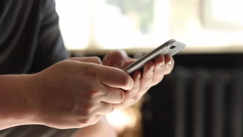 Close-up of hands typing on a smartphone screen with soft natural light Stockbeeldmateriaal 342280522