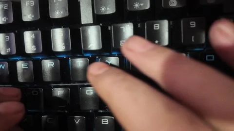 Close-up of hands typing on a vibrant RGB mechanical gaming keyboard,  focu.. Stock Footage 328847343