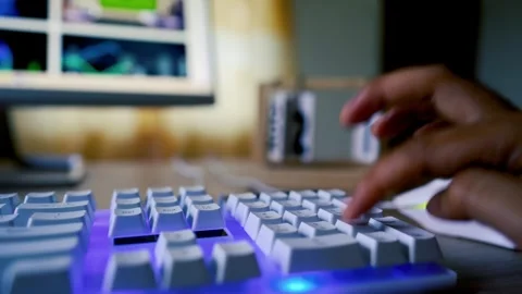 Close-up of hands typing on a white keyboard with a glowing blue backlight,.. Stock Footage 315981565