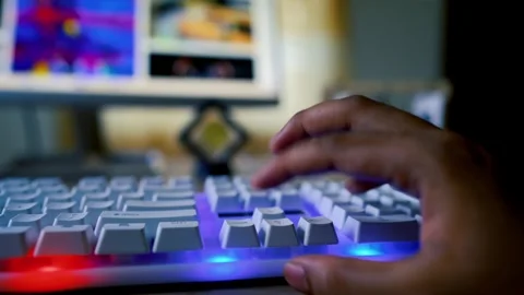 Close-up of hands typing on a white keyboard with a glowing blue backlight,.. Stock-Footage 315981582