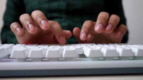 Close-up of hands typing on a white keyboard, wearing a green plaid shirt Stock Footage 320724794