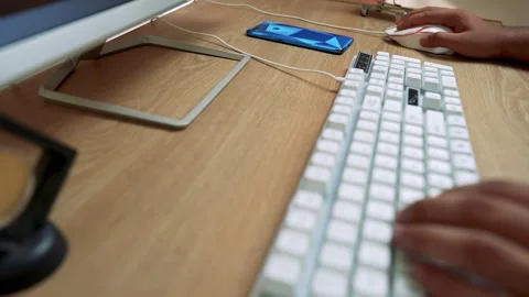 Close-up of hands typing on a white mechanical keyboard on a wooden desk Vídeo Stock 315981480
