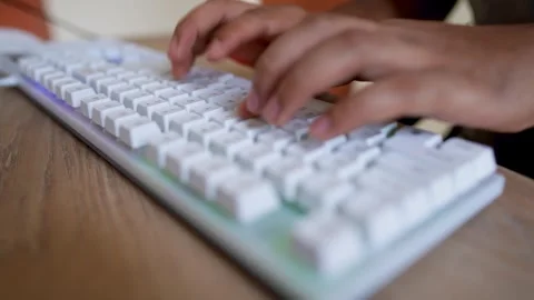 Close-up of hands typing on a white mechanical keyboard on a wooden desk Stock Footage 315982048