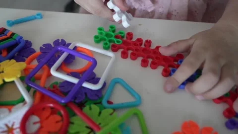Close up on hands of unknown child play with Interlocking plastic toys Video stock 247022111