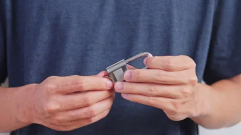 Close-up of hands unlocking metal padlock with small key for Cyber Security Stock Footage 328553024