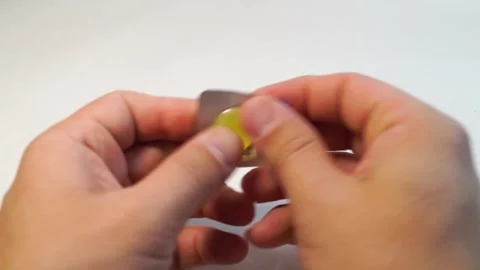 Close-up, hands unpacking a yellow pill from a package on a white background Stock Footage 171055448