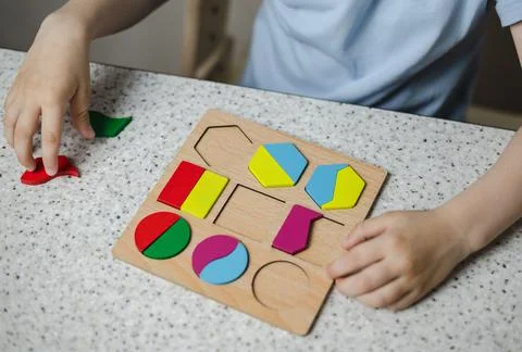 Close-up of hands of unrecognizable child inserting wooden blocks into the gr Stock Photos