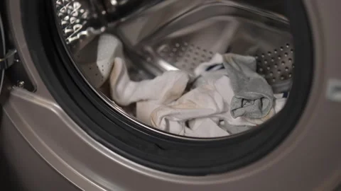 Close-up hands of unrecognizable housekeeper loading laundry into washing Stock Footage 292692887