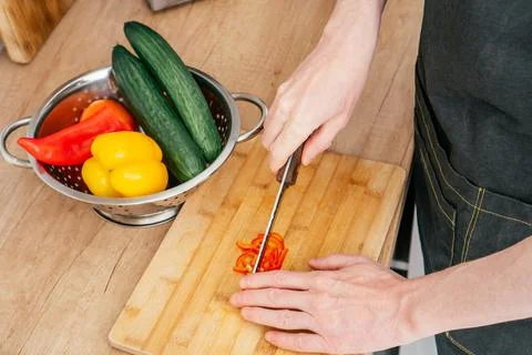 Close up of hands of unrecognizable man chop red bell pepper with knife on Stock Photos