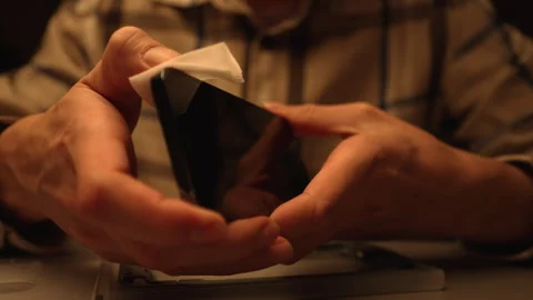 Close-up hands of unrecognizable man cleaning smartphone screen and frame with Stock Footage 305506780