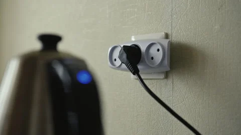 Close-up hands of unrecognizable man inserting black electric plug into white Stock Footage 311053472