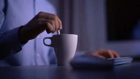 Close-up of hands unrecognizable man mixing coffee in cup during working on Stock Footage 146353447