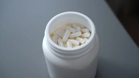 Close-up hands of unrecognizable man taking white pill from plastic bottle full Stock Footage 301394733