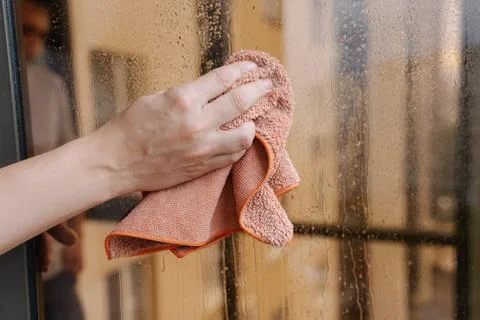 Close-up hands of unrecognizable man using orange microfiber cloth wiping drops Stock Photos
