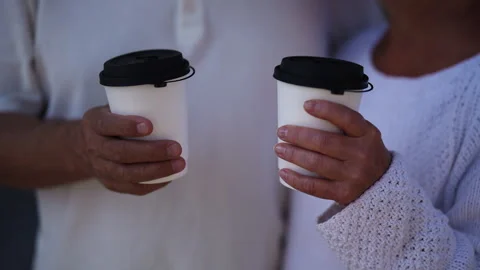 Close-up hands of unrecognizable senior couple holding white coffee cups Stock Footage 285741972